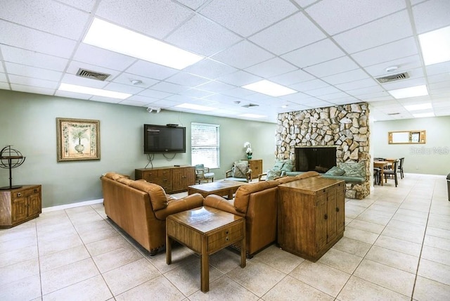 living room with light tile patterned floors, visible vents, a paneled ceiling, and a fireplace