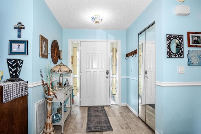 entrance foyer featuring a textured ceiling, baseboards, and wood finished floors