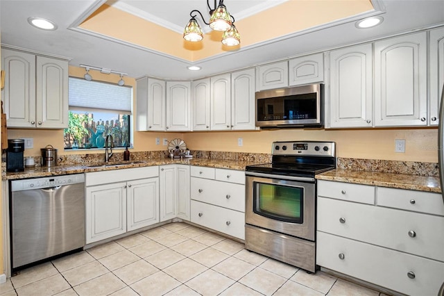 kitchen with decorative light fixtures, appliances with stainless steel finishes, a sink, light tile patterned floors, and dark stone countertops