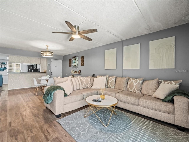 living area with a textured ceiling, ceiling fan, and wood finished floors