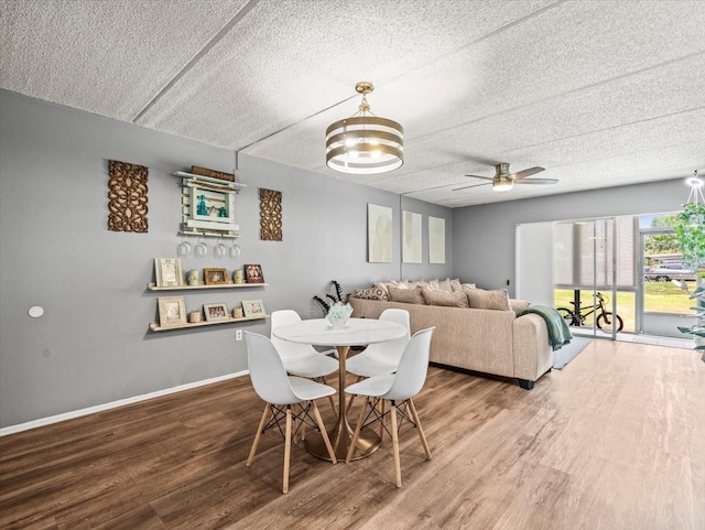 dining space featuring baseboards, a textured ceiling, ceiling fan, and wood finished floors