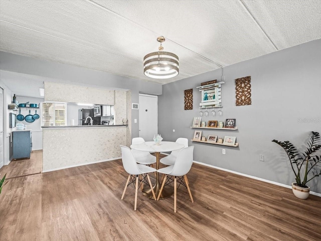 dining space featuring baseboards, a textured ceiling, an inviting chandelier, and wood finished floors