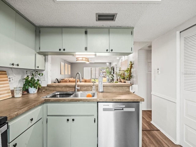 kitchen with a textured ceiling, visible vents, stainless steel dishwasher, a sink, and dark wood-style floors