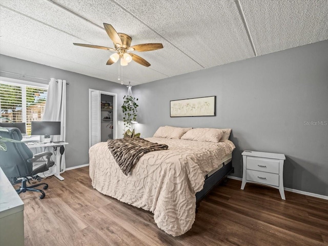 bedroom with a textured ceiling, baseboards, a closet, and wood finished floors
