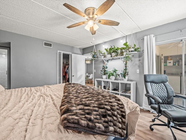 bedroom with visible vents, a closet, wood finished floors, ceiling fan, and a textured ceiling