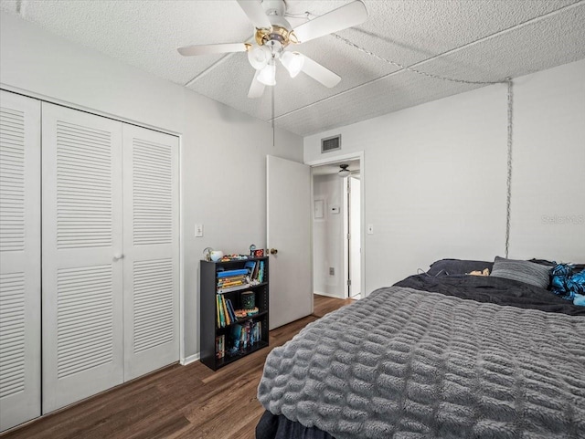 bedroom featuring visible vents, a closet, wood finished floors, a textured ceiling, and a ceiling fan