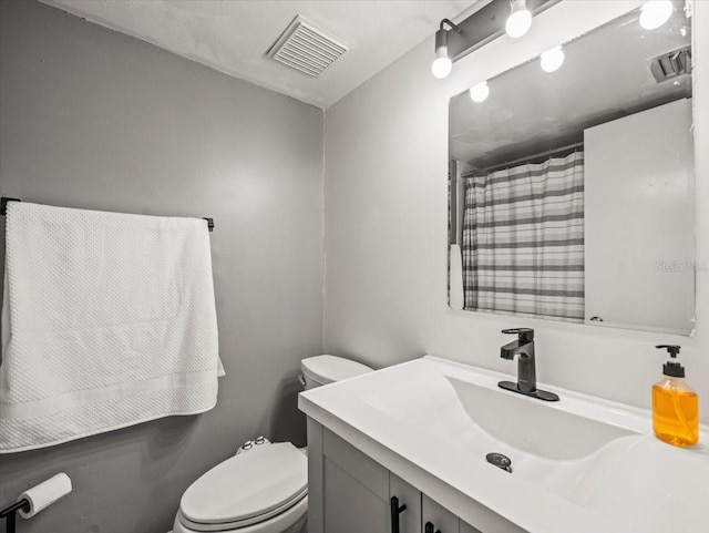 full bath featuring vanity, toilet, curtained shower, and visible vents