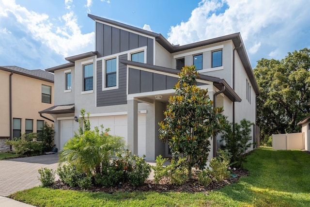 21590 Violet Periwinkle Dr, Land O Lakes, FL 34637 - contemporary home featuring a garage, a front lawn, decorative driveway, stucco siding, and board and batten siding