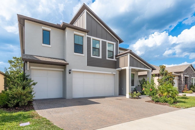 21590 Violet Periwinkle Dr, Land O Lakes, FL 34637 - view of front of home with an attached garage, decorative driveway, board and batten siding, and stucco siding