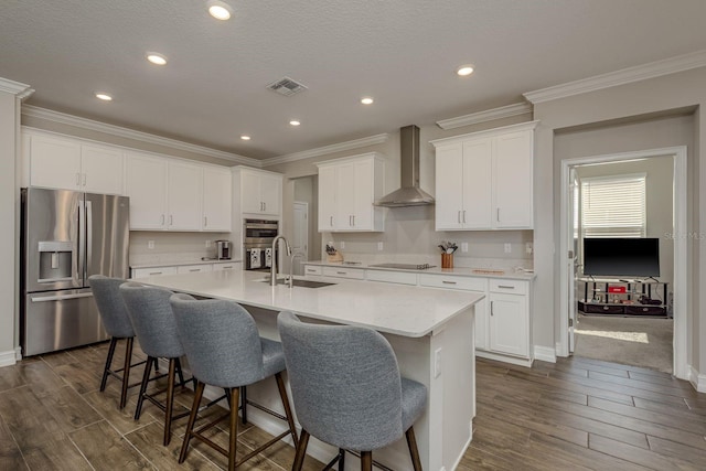 21590 Violet Periwinkle Dr, Land O Lakes, FL 34637 - kitchen featuring wall chimney range hood, crown molding, dark wood finished floors, stainless steel appliances, and white cabinetry