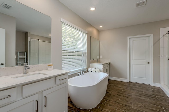 21590 Violet Periwinkle Dr, Land O Lakes, FL 34637 - bathroom with visible vents, a sink, a stall shower, and wood finished floors