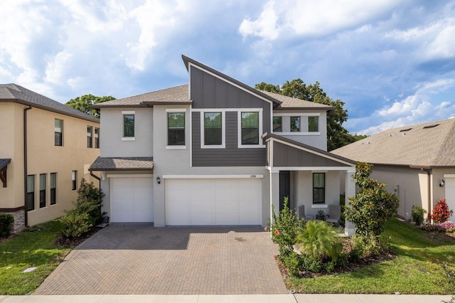 21590 Violet Periwinkle Dr, Land O Lakes, FL 34637 - view of front of home featuring a shingled roof, a garage, board and batten siding, stucco siding, and decorative driveway