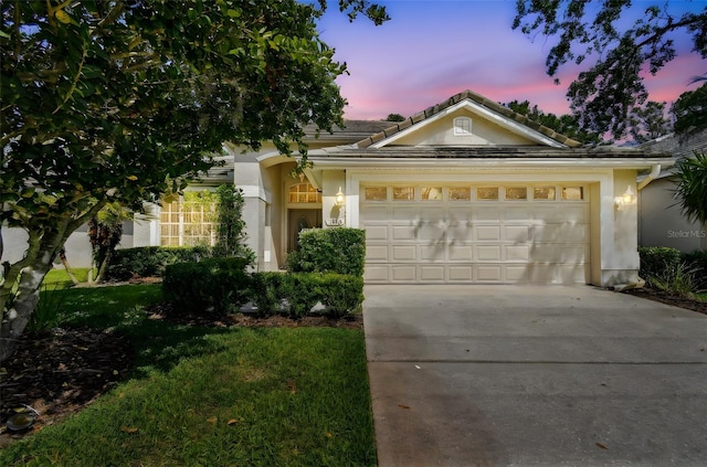 ranch-style home featuring concrete driveway, an attached garage, stucco siding, and a front lawn