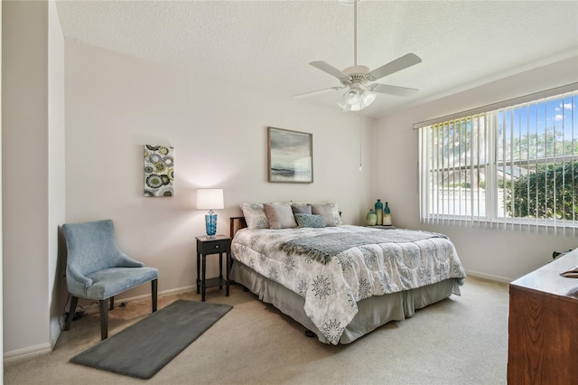 bedroom with a textured ceiling, light carpet, baseboards, and ceiling fan