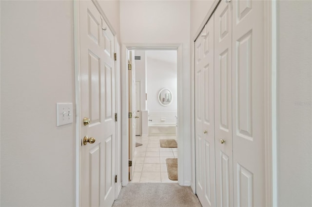 corridor with light carpet and light tile patterned flooring