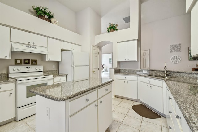 kitchen with under cabinet range hood, white appliances, light tile patterned flooring, a sink, and a high ceiling