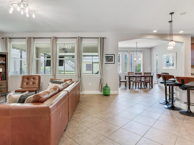 living area with arched walkways, a chandelier, recessed lighting, baseboards, and light tile patterned floors