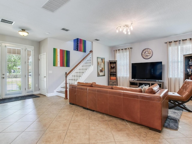 living room with stairway, light tile patterned flooring, and visible vents