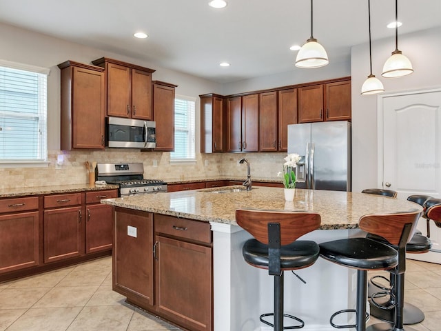 kitchen with light stone counters, a sink, appliances with stainless steel finishes, and backsplash
