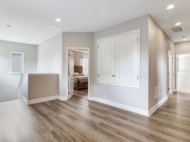 hallway with baseboards, light wood-style flooring, and visible vents