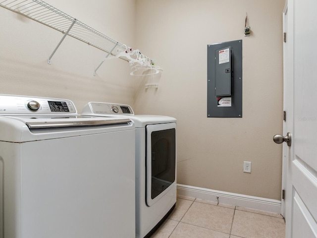 washroom with laundry area, light tile patterned flooring, baseboards, electric panel, and washing machine and clothes dryer