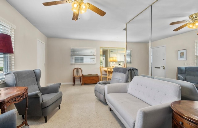 living area featuring baseboards, light carpet, and a ceiling fan