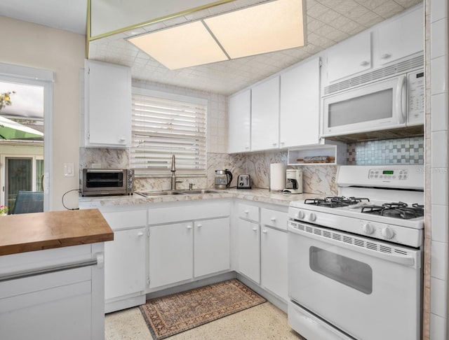 kitchen featuring white appliances, white cabinets, decorative backsplash, and a sink