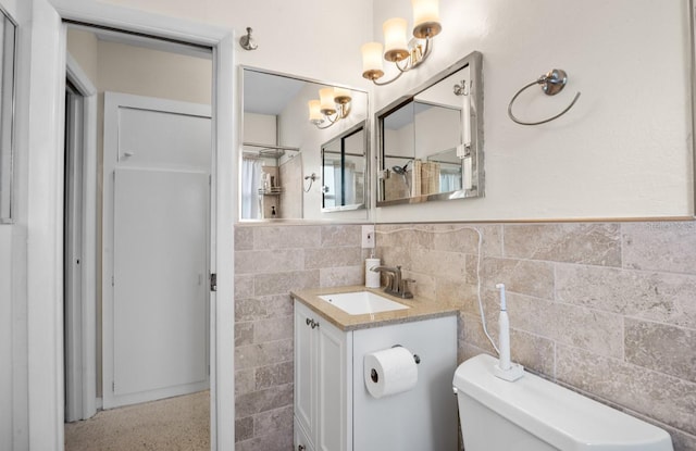 bathroom with toilet, a notable chandelier, tile walls, and wainscoting