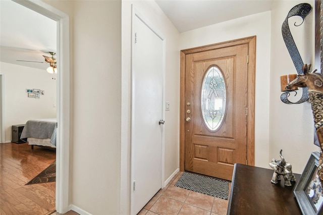 entryway featuring a ceiling fan, baseboards, and light tile patterned floors