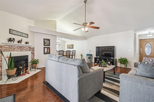 living area featuring a ceiling fan, dark wood-style flooring, a wealth of natural light, a fireplace with flush hearth, and vaulted ceiling
