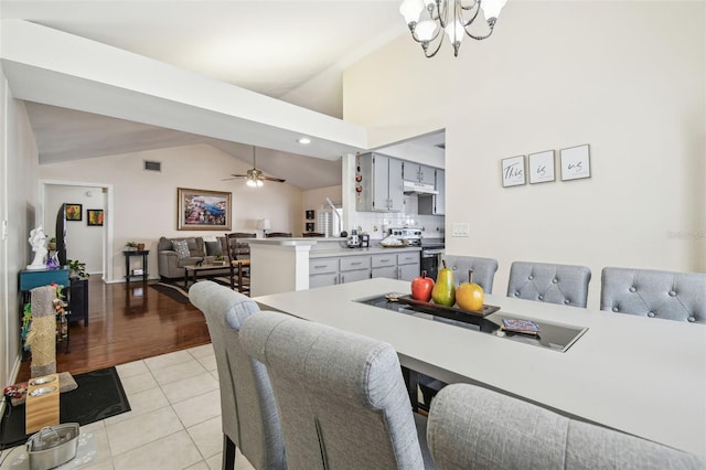 dining area featuring visible vents, ceiling fan with notable chandelier, light tile patterned floors, and lofted ceiling