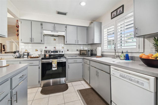 kitchen with appliances with stainless steel finishes, under cabinet range hood, and gray cabinetry
