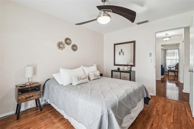 bedroom featuring a ceiling fan, baseboards, visible vents, and wood finished floors
