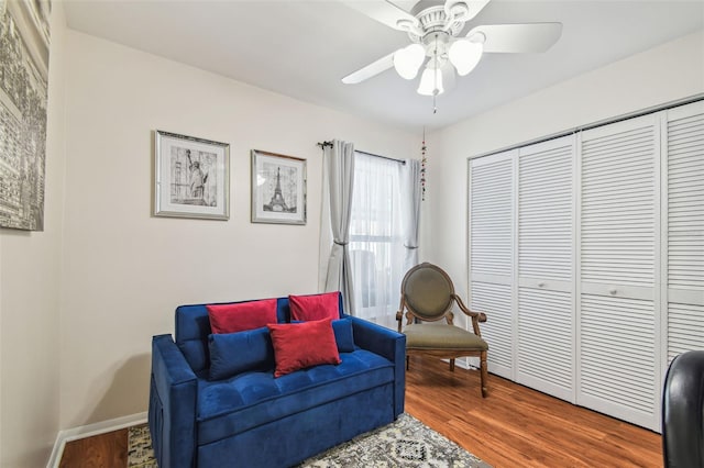 living area with baseboards, a ceiling fan, and wood finished floors