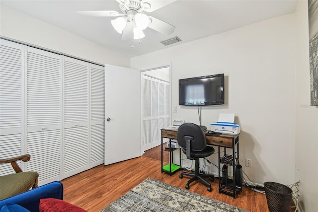 home office with a ceiling fan, wood finished floors, and visible vents