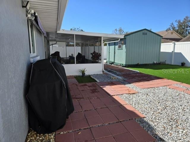 view of patio with a sunroom, an outdoor structure, a shed, and fence