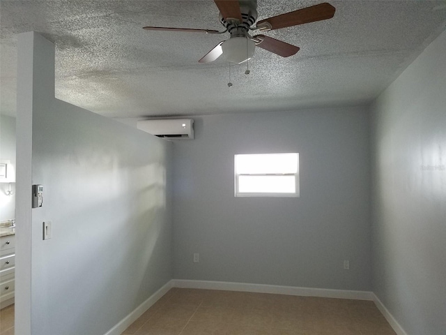spare room featuring ceiling fan, a textured ceiling, a wall mounted AC, light tile patterned floors, and baseboards