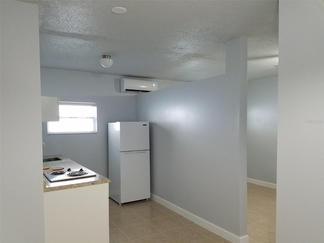 kitchen with freestanding refrigerator, a textured ceiling, a wall mounted AC, and electric stovetop