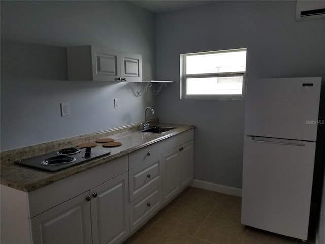 kitchen featuring a wall mounted AC, a sink, white cabinets, freestanding refrigerator, and electric cooktop