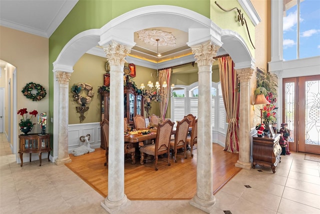 dining room featuring ornamental molding, a towering ceiling, ornate columns, tile patterned floors, and arched walkways