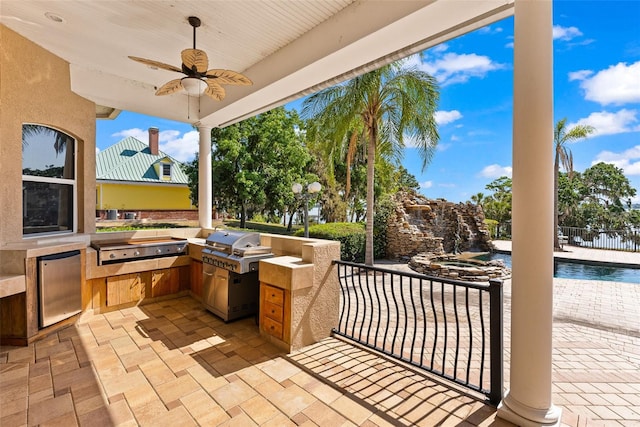 view of patio with fence, exterior kitchen, grilling area, an outdoor pool, and a ceiling fan