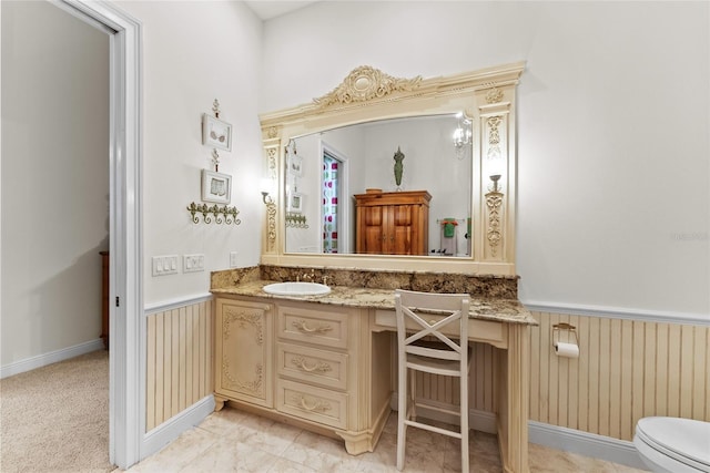 bathroom featuring vanity, a wainscoted wall, and toilet