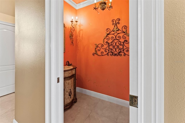 bathroom featuring tile patterned flooring, ornamental molding, vanity, baseboards, and a notable chandelier