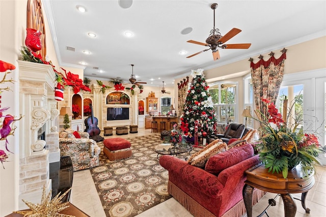 living area with crown molding, a ceiling fan, visible vents, and a fireplace
