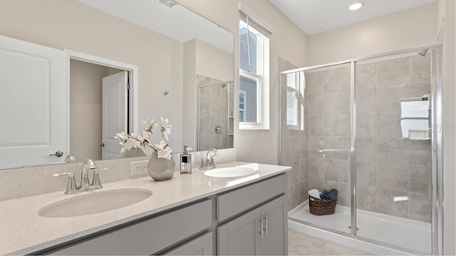 bathroom featuring double vanity, a sink, a stall shower, and tile patterned floors