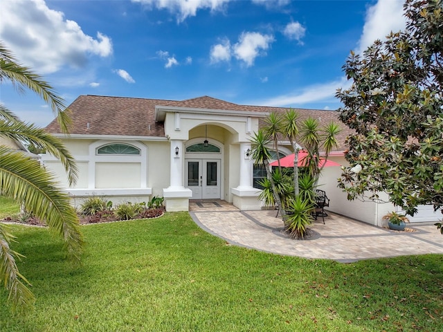 mediterranean / spanish home with a front lawn, a shingled roof, stucco siding, and french doors