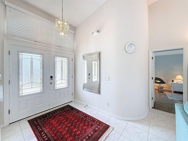 entrance foyer featuring an inviting chandelier, a textured ceiling, baseboards, and high vaulted ceiling