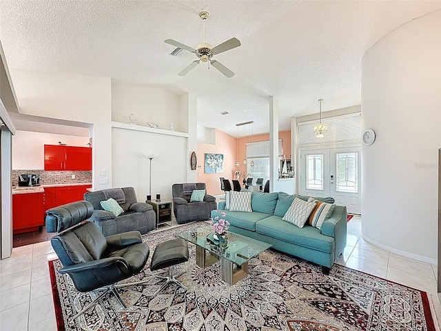 living area featuring lofted ceiling, ceiling fan, light tile patterned flooring, and a textured ceiling