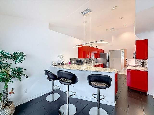 kitchen with a peninsula, stainless steel refrigerator with ice dispenser, a toaster, backsplash, and light countertops