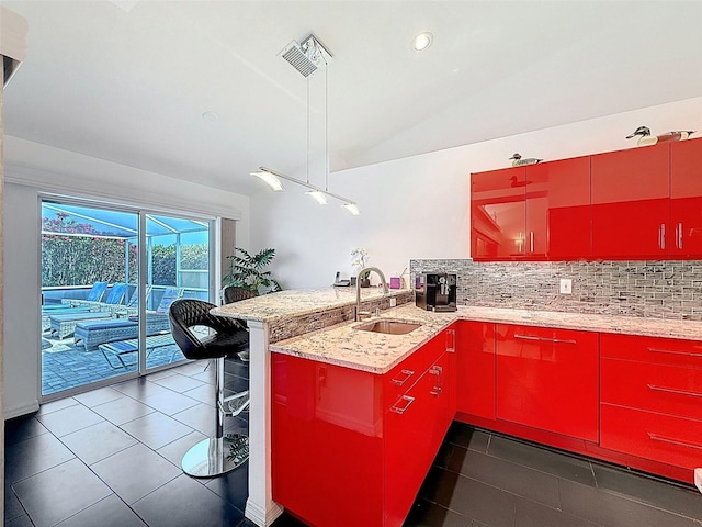 kitchen with a sink, a peninsula, tile patterned flooring, backsplash, and red cabinets